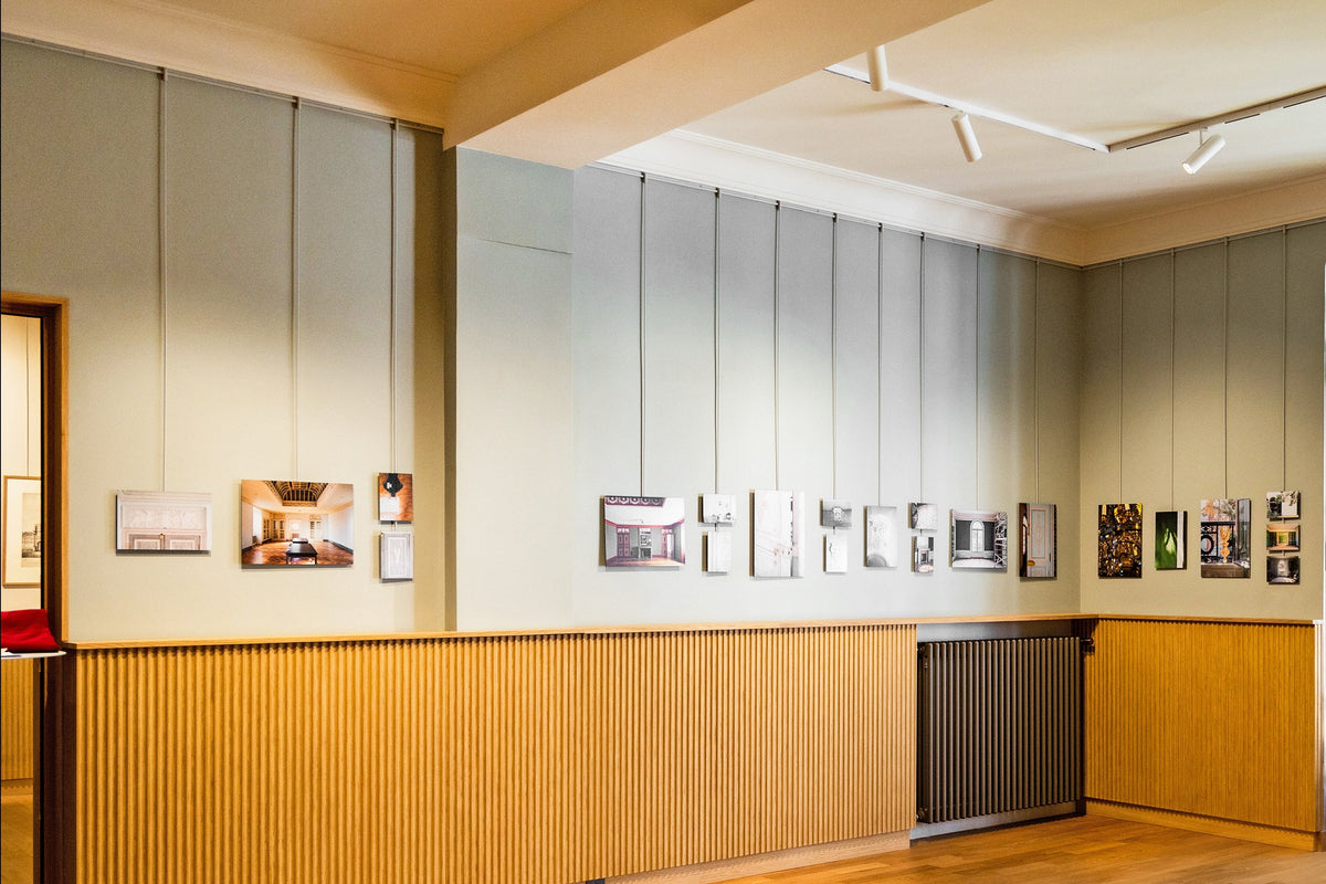 Exposition de photos dans un musée accroché par des tiges sur cimaise aux couleurs des murs de la Maison Boyer